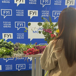 Back of a woman holding flowers in front of a FYI step and repeat