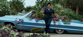 Black woman in front of a flower installation in a low rider car