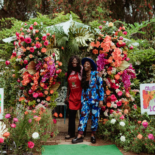 Two black woman in front of a flower installation