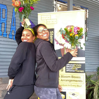 Two young black girls smiling at the camera with flowers