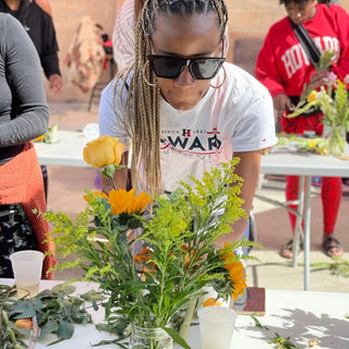 Black woman with glasses looking at flowers