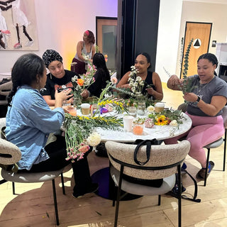 A group of black woman sitting around a table in a flower workshop