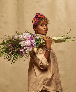 Black florist Talia Boone holding a bouquet of flowers over her shoulder
