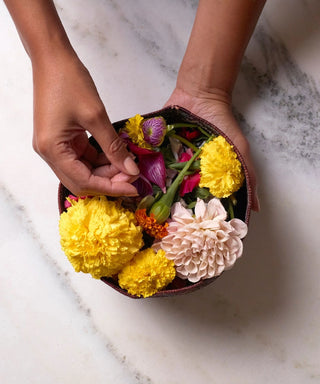 Black hand holding a bowl of flowers